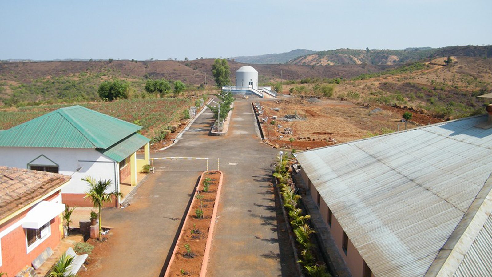 Road through the Anandkunj campus with buildings and hills behind