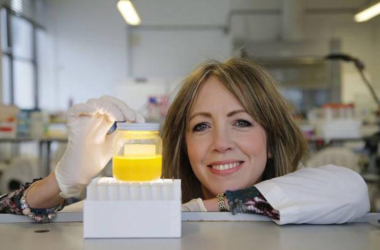Smiling researcher beside a sample in a laboratory