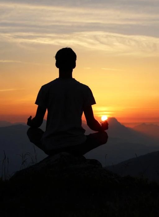 Silhouette of a person meditating at sunrise