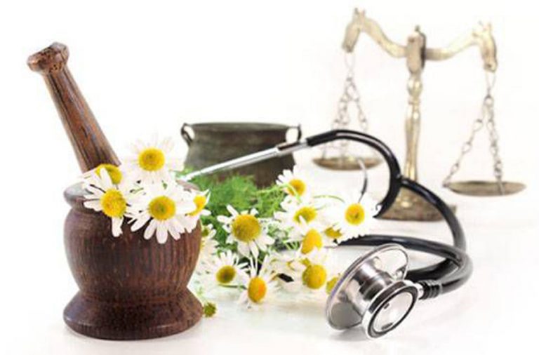 Mortar and pestle with chamomile flowers, scales and a stethoscope