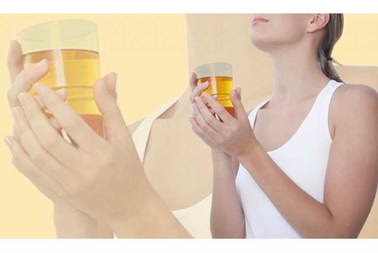 Woman holding a glass of pale yellow liquid